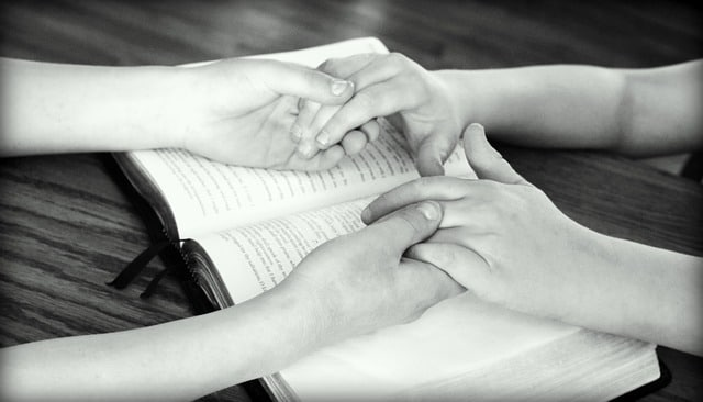 Photo of people holding hands in prayer over Bible in an article on prayer by the Church of Christ Santa Clara Truthseekers SCCOC